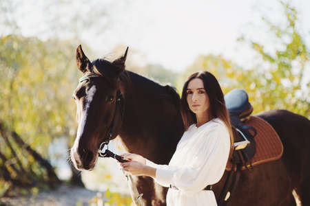 Portrait of cute woman holding horse by the rainsの写真素材