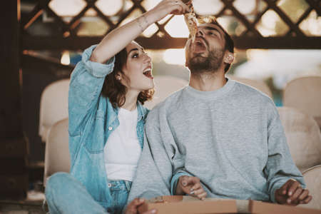 Attractive young couple eating a fresh pizza outdoors.