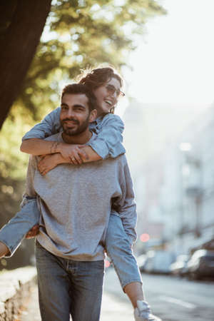Young man giving girlfriend piggyback rideの写真素材