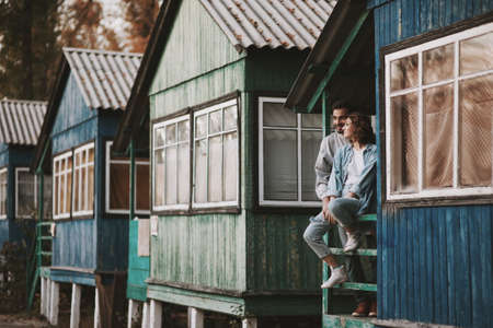 Romantic couple sitting on porch of wooden cabin.の写真素材