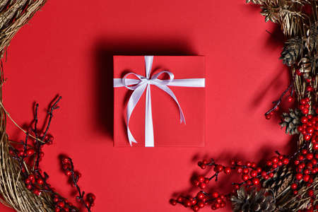 Top view of gift box with christmas wreath on red backgroundの写真素材