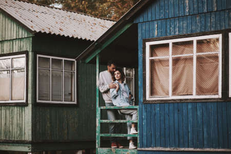 Romantic couple standing on porch of wooden cabin.の写真素材