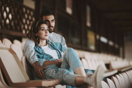 Portrait of romantic couple sitting together on empty sports tribune