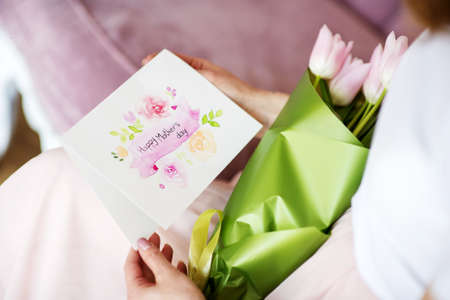 Female hands holding handmade greeting card for Mothers Day.