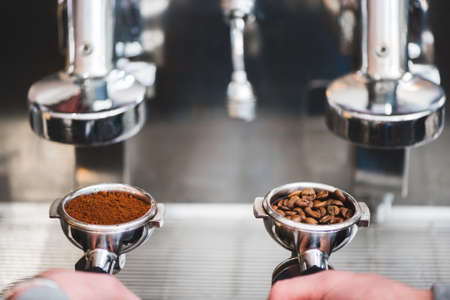 Close up photo barista hands holding a portafilters with ground coffee and coffee beans.の写真素材