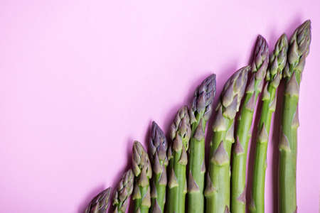 Green fresh asparagus in row on pink backgroundの写真素材