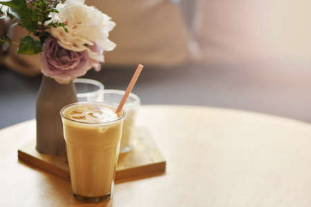Glass of cold coffee on wooden table in cafe