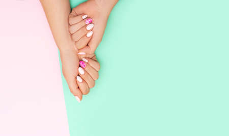 Top view of perfect manicure with trendy nail art on pink and turqoise background