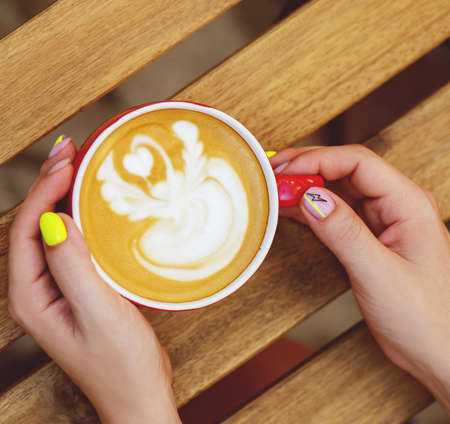 Female hands with trendy neon manicure holding cup of coffee.