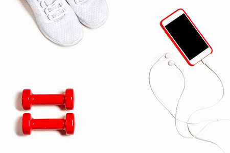 Flat lay composition with sneakers, headphones, mobile phone and red dumbbells on white background.の写真素材