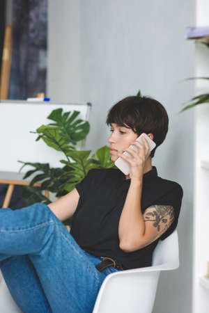 Pretty young businesswoman talking on phone sitting at the office.の写真素材