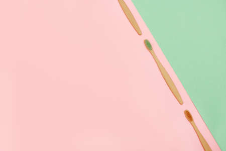 Set of bamboo toothbrushes in a row on pink and turquoise background. Top view.の写真素材