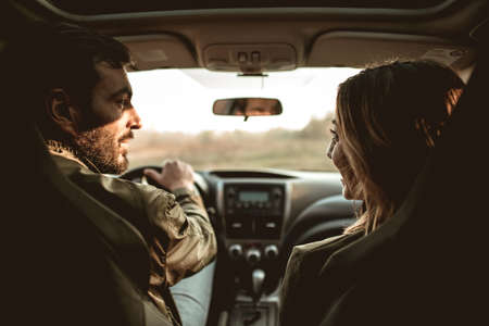 Young couple sitting on front passenger seats and looking at each other.の写真素材