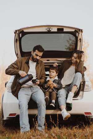Young family with cute son having picnic in car trunk.の写真素材