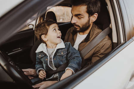 Father playing with son in drivers seat in his car.の写真素材