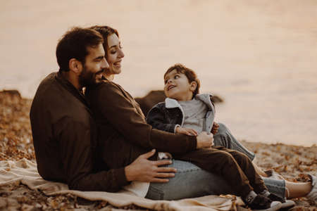 Young family sitting by the river in autumn day.の写真素材