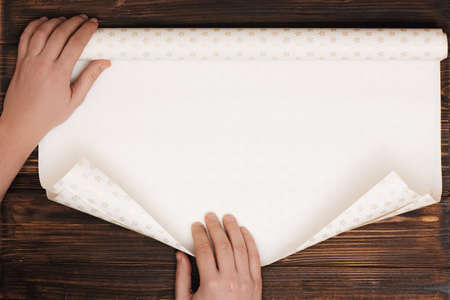 Manss hands unfolding paper for wrapping present.