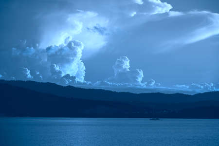 Seashore with tropical forest and fluffy clouds toned in blue.の写真素材