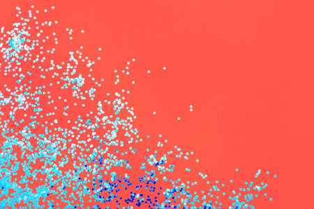 Blue shiny sequins on coral background with copy space.