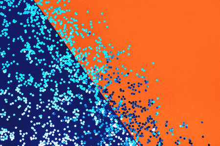 Flat lay with shiny sequins on blue and orange background with copy space.