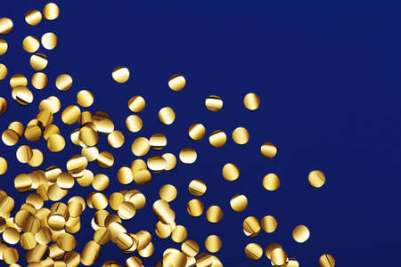 Golden shiny confetti scattering on blue background.の写真素材