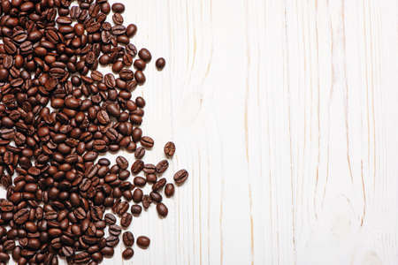 Roasted coffee beans on white wooden background with copy space.