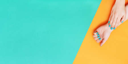 Banner made of perfect manicure with trendy nail art on orange and green background with copy space.の写真素材