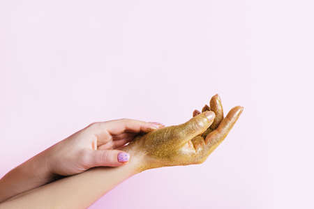 Perfect manicure with trendy nail art and hand with golden glitter on pink background with copy space.の写真素材