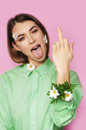 Young beautiful woman with flowers on her face showing middle finger gesture.