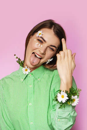Young beautiful woman with flowers on her face showing middle finger gesture.