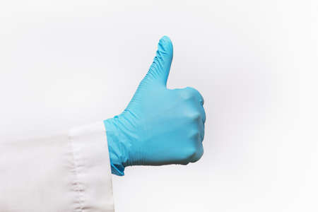 Partial view of hand wearing blue latex glove giving thumbs up.の写真素材