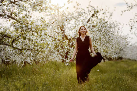 Beautiful smiling woman in the blooming apple garden.