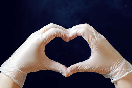 Doctors hands making heart shape on black background.
