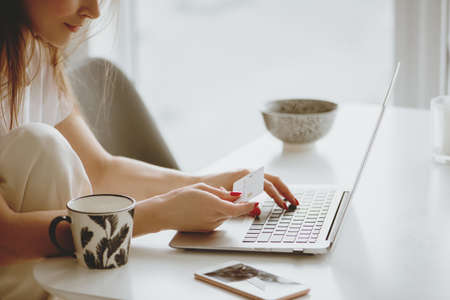 Partial view of woman inputting card information while shopping online.