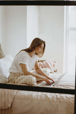 Woman working on laptop on the bed.の写真素材