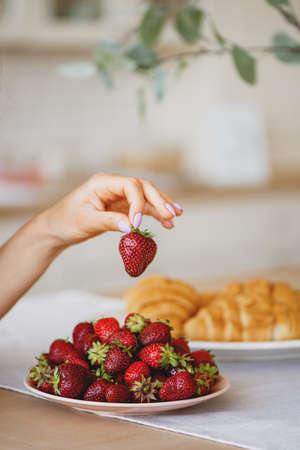 Woman hand holding red fresh strawberry.