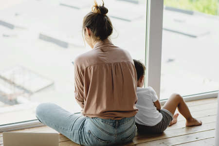 Mother and son sitting on the floor near the window.の写真素材