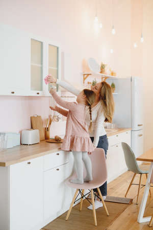 Little girl and her mother cleaning up the kitchen.の写真素材