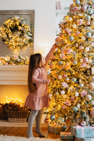 Cute little girl hanging Christmas tree toy on Christmas tree.の写真素材