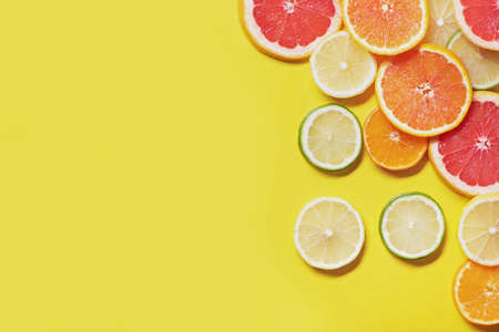 Slices of citrus fruits on yellow background.の写真素材