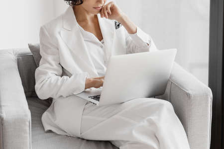 Cropped portrait of businesswoman working with laptop while siting in chair in office.