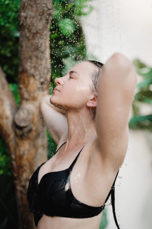Beautiful woman standing under shower outdoors.
