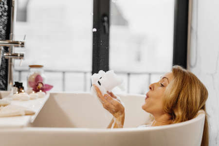 Closeup of woman blowing soap bubbles in bath at home.の写真素材