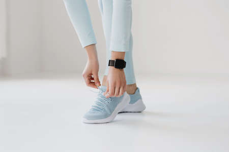 Low section of sporty woman tying shoelace on white background.の写真素材
