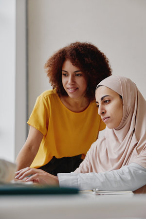 Multiracial young female colleagues working together at laptop.の写真素材