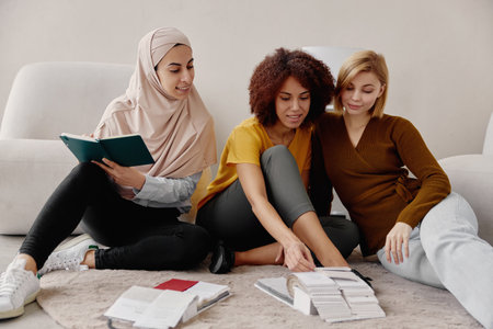 Multiethnic female designers working together and choosing textile samples in office.