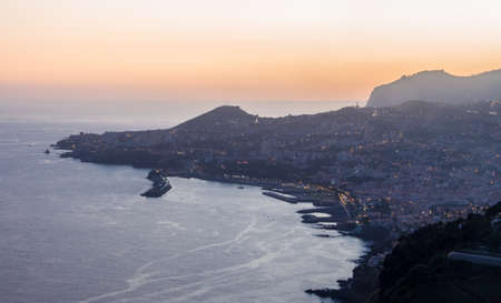 Sunset View at island of madeira looking in sunset over the bay of Funchal with sea view. the last sun rays of the beautiful day shining down on the Atlantic Ocean. Perfect concept for traveling madeira or outdoor concept. autumn light.の写真素材