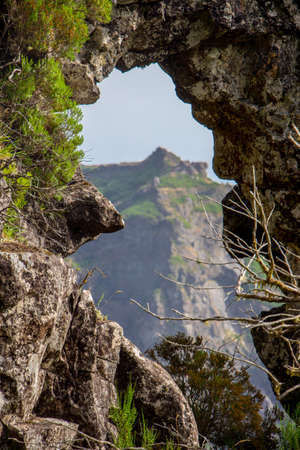 Natural frame. Hiking in madeira central mountains with beautiful landscape, horizon, blue sky on the way. Spectacular madeira mountainscape, green trees, small madeiran villages.の写真素材