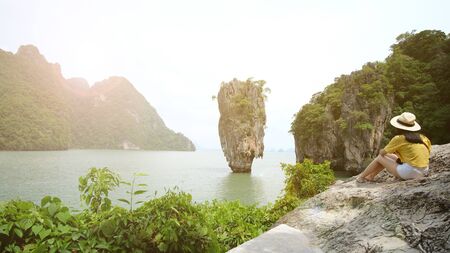 Thailand Phang Nga 3 Nov 2018, a female traveler wearing a yellow shirt, is taking a photo of herself with mountain and sea views in Phang Nga Province, Thailand.のeditorial素材