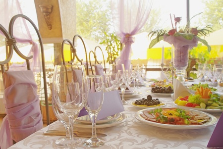 Table set for a wedding dinner decorated with flowers and a silk bow の写真素材